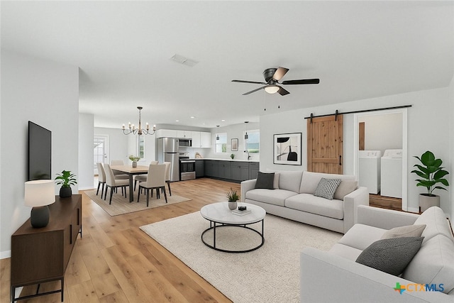 516 Tampico St, Seguin, TX 78155 - living area featuring washer and dryer, a chandelier, a barn door, ceiling fan, and light wood-style flooring