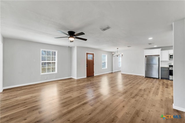 unfurnished living room featuring a wealth of natural light, visible vents, and light wood finished floors