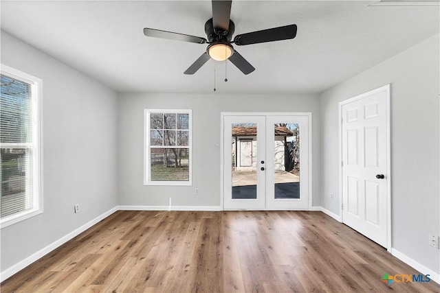 unfurnished room with wood finished floors, french doors, and baseboards