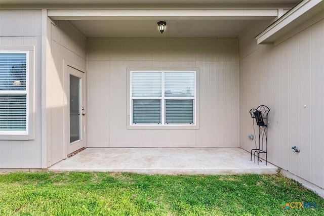 doorway to property with a lawn and a patio
