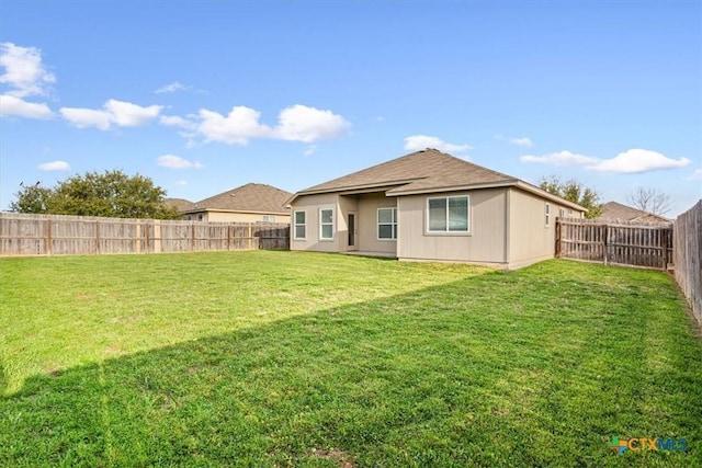 back of property featuring a fenced backyard and a yard