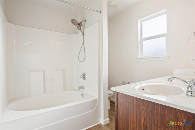 full bathroom featuring double vanity, toilet, wood finished floors, a sink, and shower / tub combination
