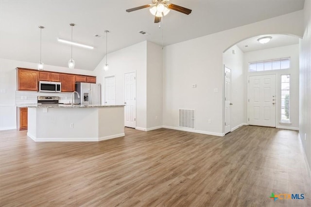kitchen featuring visible vents, light wood finished floors, stainless steel appliances, a ceiling fan, and arched walkways