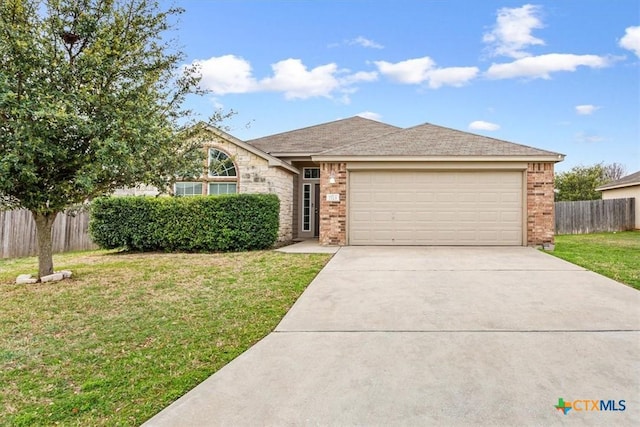 view of front of home featuring fence, an attached garage, brick siding, a front lawn, and driveway