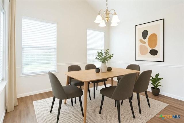 dining space featuring light wood finished floors, a healthy amount of sunlight, and a chandelier