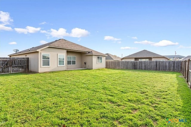 back of house with a fenced backyard and a lawn