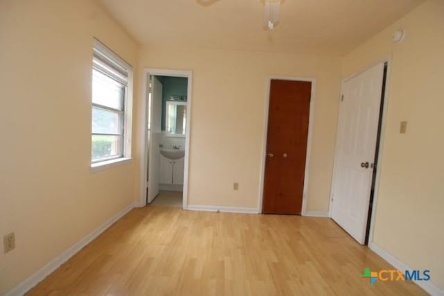 1007 E Robertson Ave, Copperas Cove, TX 76522 - unfurnished bedroom with light wood-style floors, baseboards, a sink, and ensuite bathroom