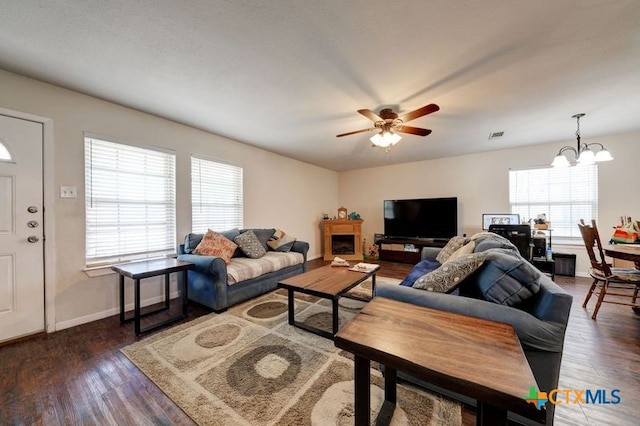 living area featuring baseboards, wood finished floors, and ceiling fan with notable chandelier