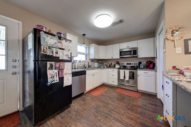 kitchen with appliances with stainless steel finishes, visible vents, dark wood finished floors, and white cabinetry