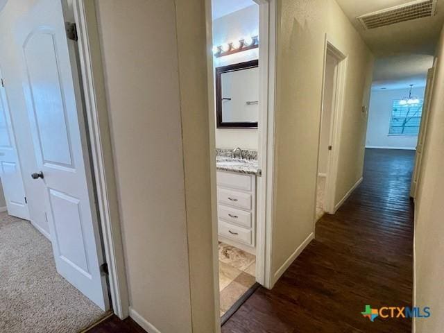1541 Cologne Dr, New Braunfels, TX 78130 - hallway featuring dark wood finished floors, visible vents, baseboards, and a sink