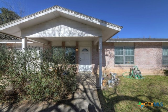 entrance to property with a yard and brick siding