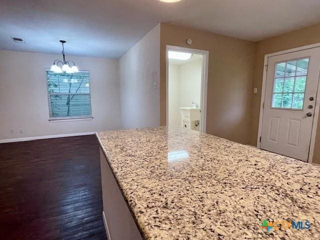 1541 Cologne Dr, New Braunfels, TX 78130 - interior space with light stone counters, visible vents, dark wood finished floors, a chandelier, and hanging light fixtures