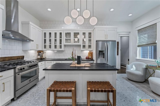 kitchen with a center island, appliances with stainless steel finishes, a breakfast bar, and wall chimney exhaust hood