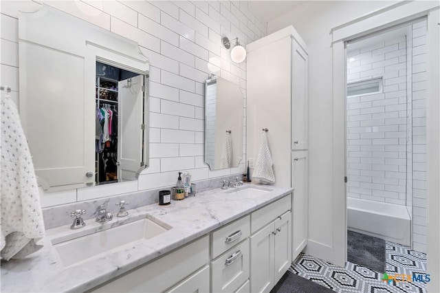 bathroom with vanity, tiled shower / bath combo, tile patterned flooring, and tile walls