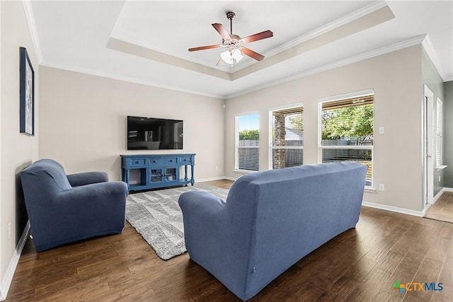 living room featuring baseboards, a tray ceiling, a ceiling fan, and wood finished floors