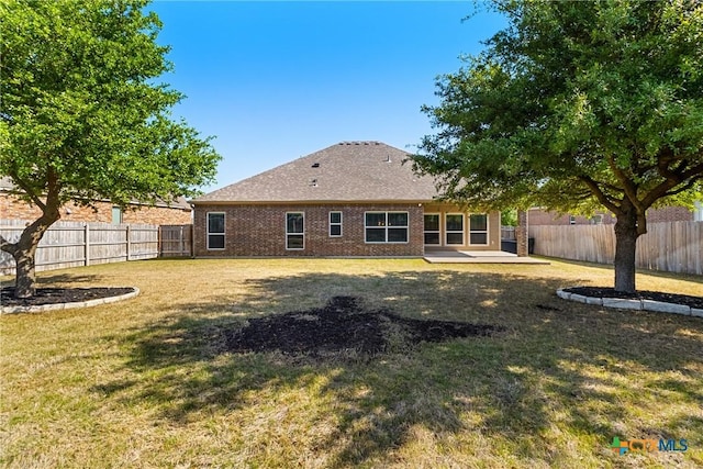 back of property with a patio area, a fenced backyard, brick siding, and a lawn