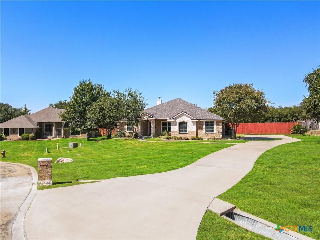 view of front of home with stone siding, a front lawn, a chimney, and fence