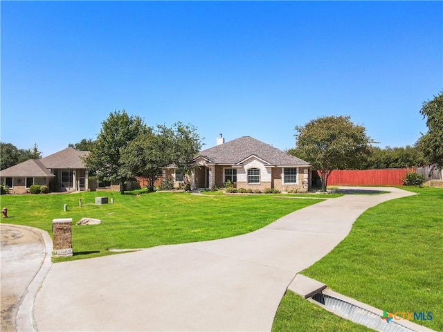 view of front of home with stone siding, a front lawn, a chimney, and fence