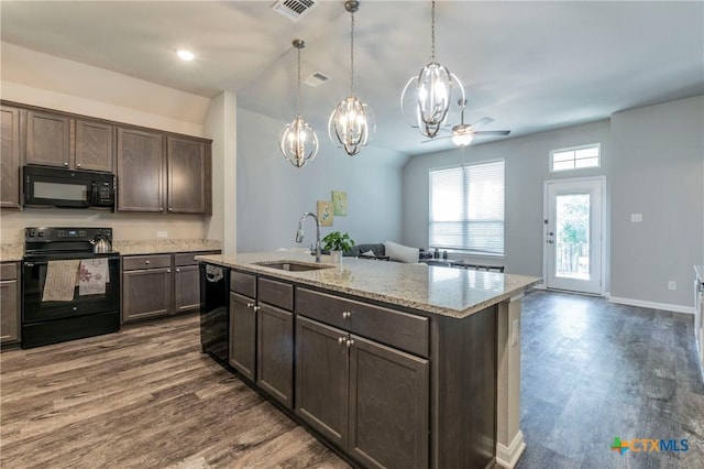 kitchen with sink, dark brown cabinetry, black appliances, a center island with sink, and decorative light fixtures