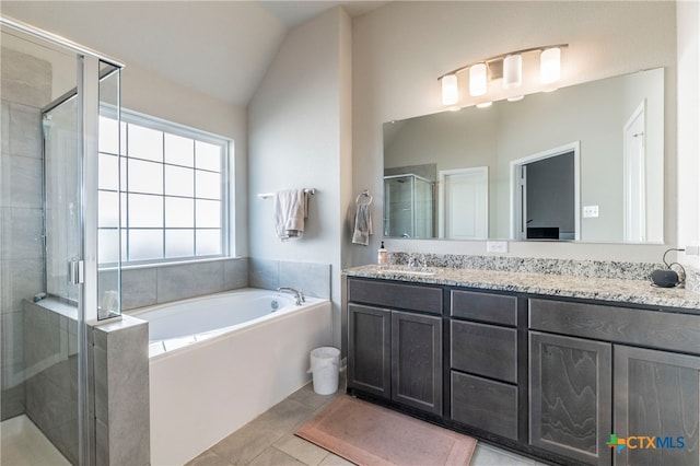 bathroom with tile patterned flooring, shower with separate bathtub, lofted ceiling, and vanity