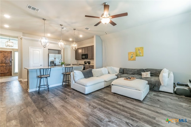 living room featuring hardwood / wood-style flooring and ceiling fan with notable chandelier