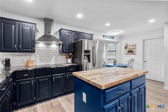 119 Larimore St, Victoria, TX 77904 - kitchen with wall chimney exhaust hood, stainless steel fridge, wooden counters, backsplash, and light wood-style flooring