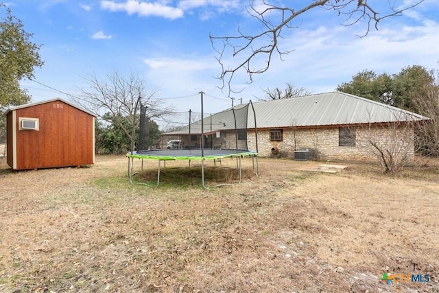 view of yard featuring central AC, a storage unit, and a trampoline