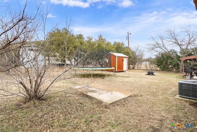 view of yard with central AC unit, a shed, and a trampoline