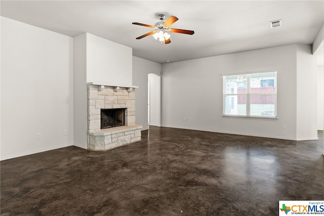 unfurnished living room featuring a stone fireplace and ceiling fan