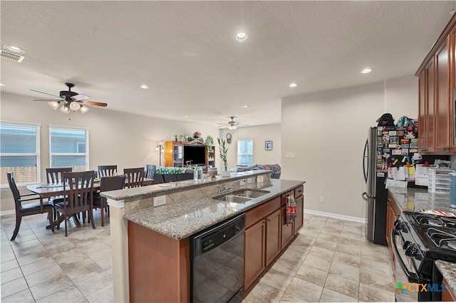 kitchen featuring light stone countertops, appliances with stainless steel finishes, plenty of natural light, and a center island with sink