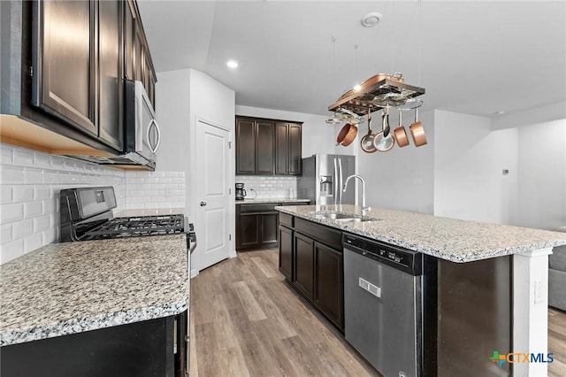 kitchen featuring decorative backsplash, stainless steel appliances, and an island with sink