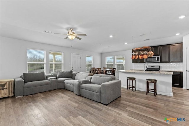 living room with light hardwood / wood-style flooring, ceiling fan, and sink