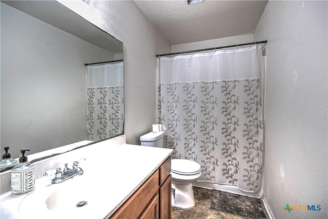 bathroom with vanity, toilet, and a textured ceiling