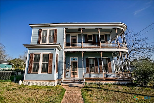 view of front facade with a porch, a balcony, and a front yard