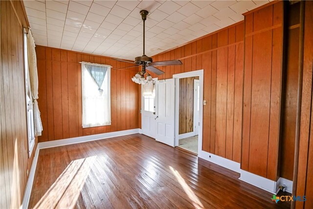 interior space featuring wood-type flooring, ceiling fan, and wood walls