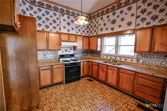 kitchen featuring light stone countertops, pendant lighting, sink, and range with gas stovetop