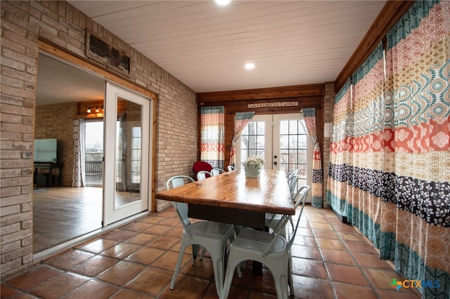 dining space featuring brick wall and french doors