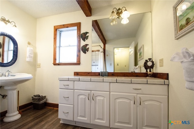 bathroom featuring sink, hardwood / wood-style floors, a textured ceiling, and beam ceiling