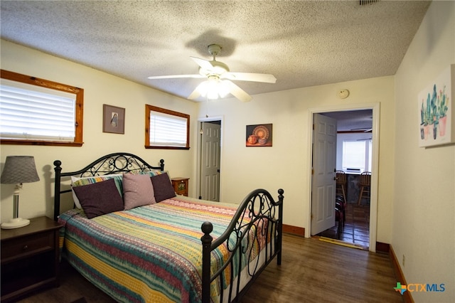 bedroom featuring ceiling fan, dark hardwood / wood-style flooring, and a textured ceiling