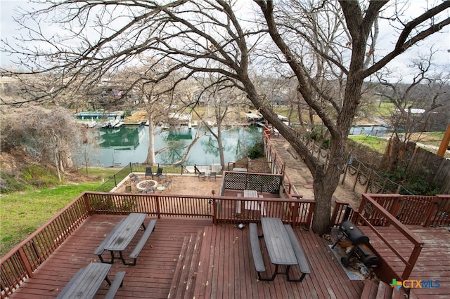 wooden deck featuring a water view, a grill, and a fire pit