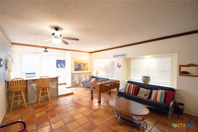 playroom featuring ceiling fan, a textured ceiling, ornamental molding, and a healthy amount of sunlight