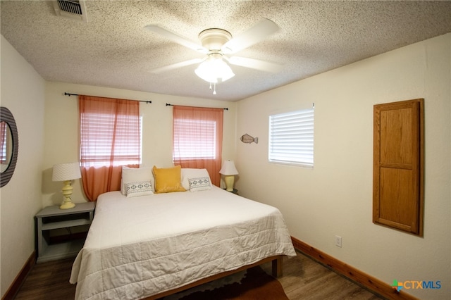 bedroom featuring dark hardwood / wood-style flooring, ceiling fan, and a textured ceiling