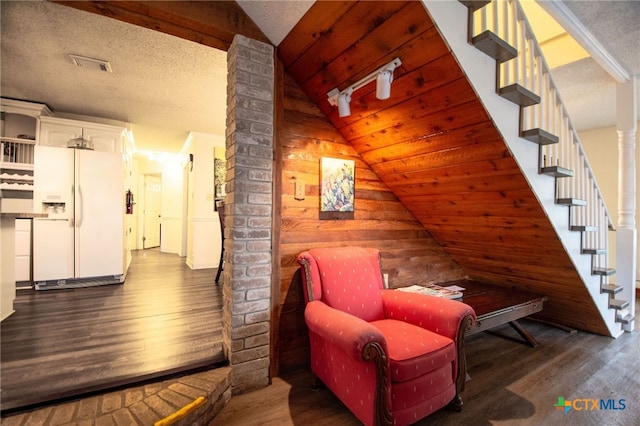 sitting room featuring vaulted ceiling, dark hardwood / wood-style floors, wooden walls, and a textured ceiling