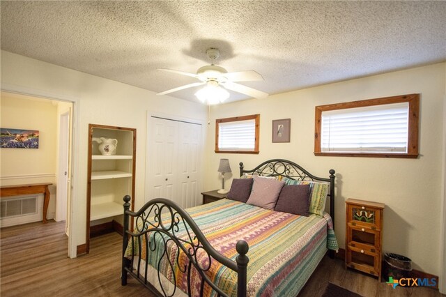 bedroom with dark wood-type flooring, a textured ceiling, and a closet