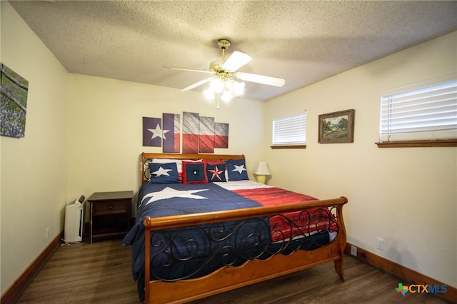 bedroom featuring dark hardwood / wood-style flooring, multiple windows, and a textured ceiling