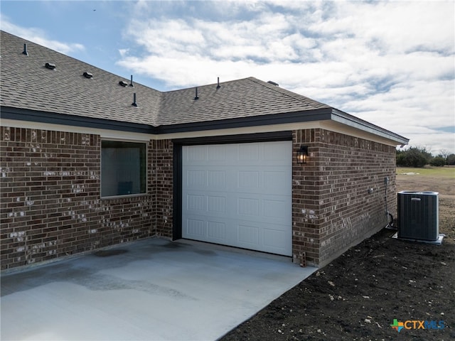 garage featuring concrete driveway and central AC unit