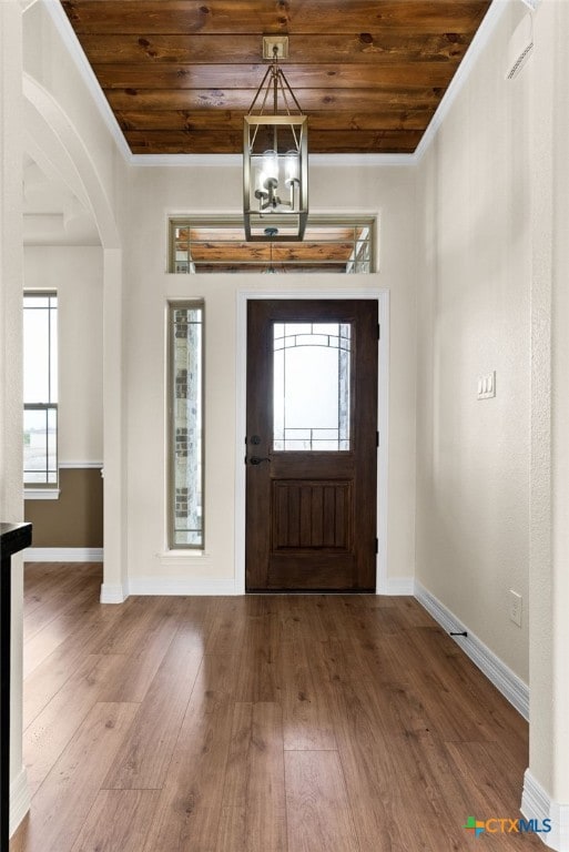 foyer featuring wooden ceiling, baseboards, arched walkways, and wood finished floors