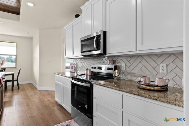 kitchen featuring stainless steel appliances, baseboards, white cabinets, backsplash, and light wood finished floors