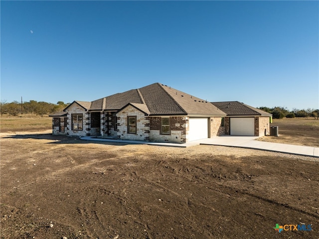 view of front of house with a garage and central air condition unit