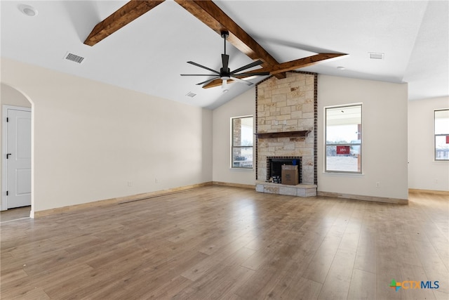 unfurnished living room featuring a fireplace, lofted ceiling with beams, light hardwood / wood-style flooring, and a healthy amount of sunlight